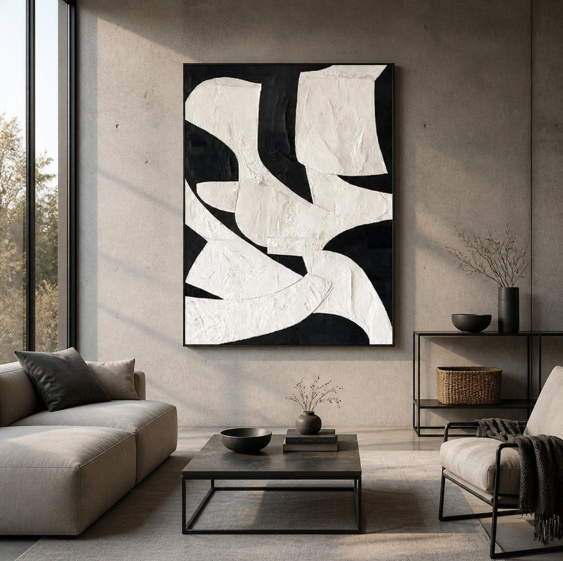 Bold black-and-white textured abstract painting above a low black console table in a wabi-sabi living room with soft concrete-toned walls