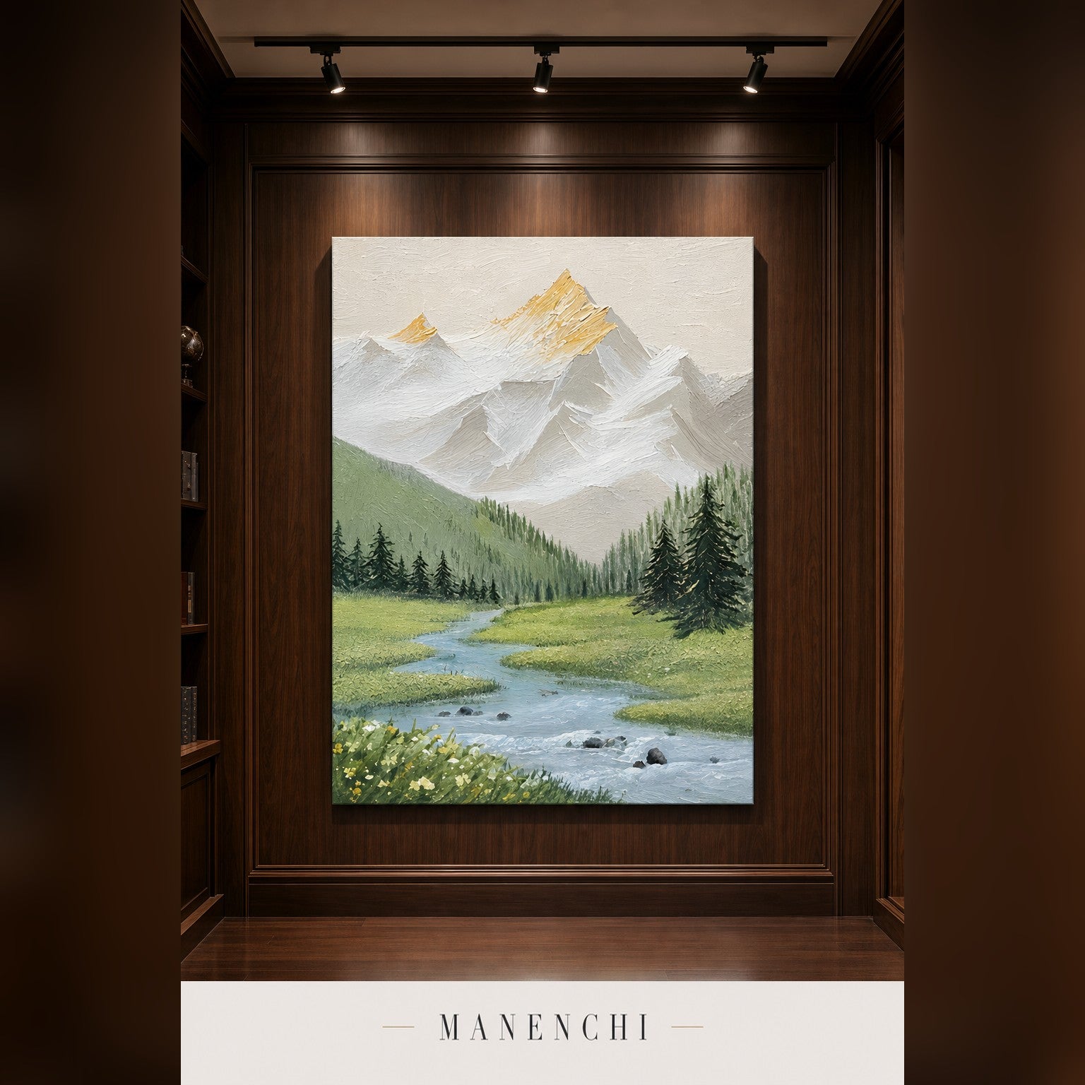 A vertical canvas painting of a mountain landscape with snowy peaks, green hills, pine trees, and a winding river, displayed on a dark wood-paneled wall under spotlights. The brand name MANENCHI appears at the bottom.